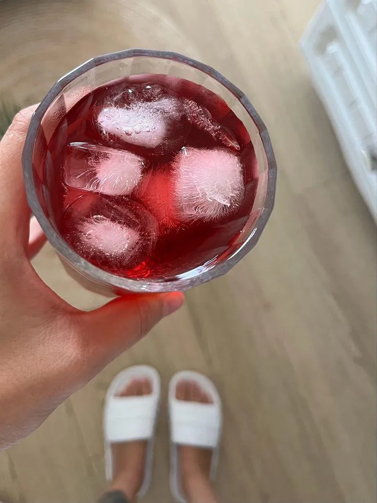 Copo do drink Holi com gelo visto de cima, segurado na mão
